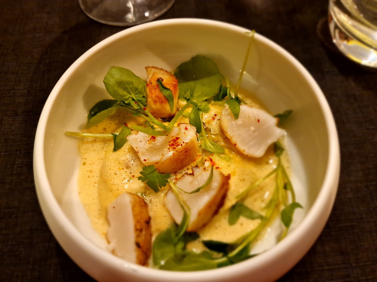 Un poisson rôti servi dans une sauce jaune avec des herbes