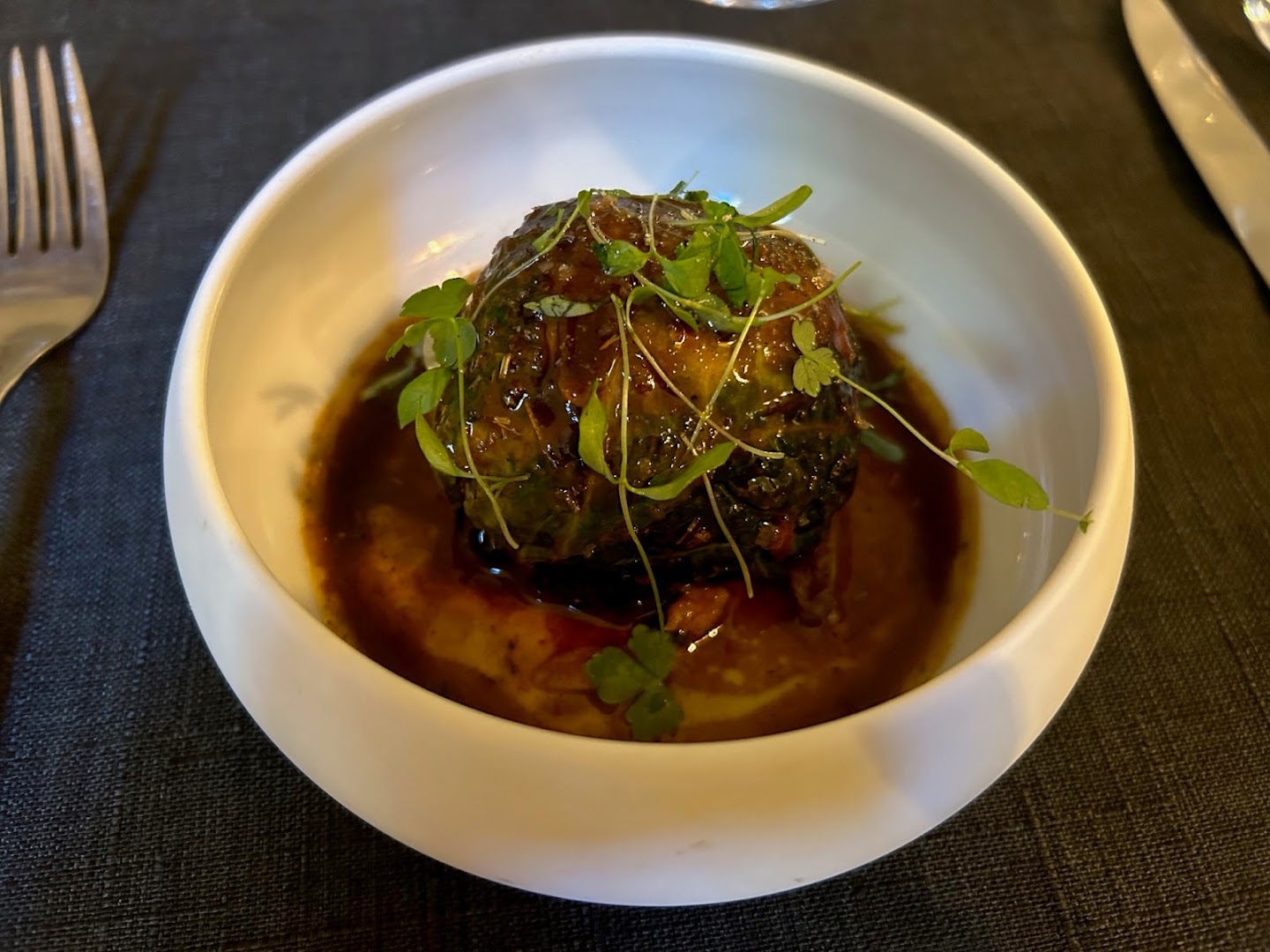 Une pièce de viande nappée de jus et couverte d’herbes